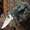 The Spyderco Para Military 2 C81GPCMO2 is shown open against a white background. The satin clip point blade with a Trademark Round Hole extends from a digital camo G-10 handle with a bright pocket clip.