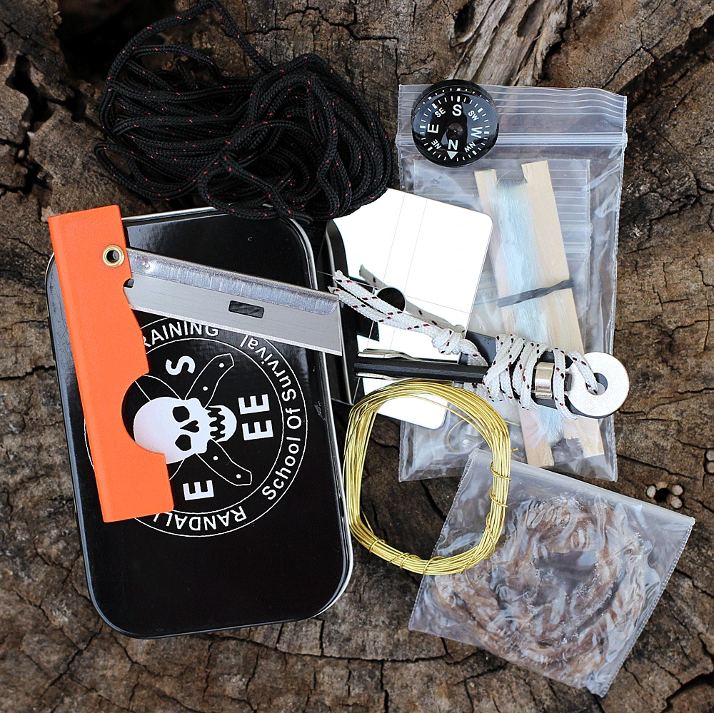 The ESEE Mini Survival Kit (ESEE-MINI-KIT) in a black pocket-size tin with the Randall's Adventure & Training logo on the lid, shown with its ferro rod and striker, signal mirror, button compass, fishing kit, snare wire, cordage, folding razor blade, Brite Strike light, and survival card.
