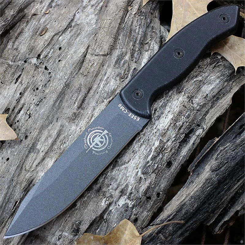 The ESEE-CM6 (ESEE-CM-6-TG-B) shown with its 5.88-inch 1095 clip point blade in a Tactical Gray finish and flat grind with a sharpened swedge, full-sized black G-10 handle scales, and its black Kydex sheath with multiple carry options.