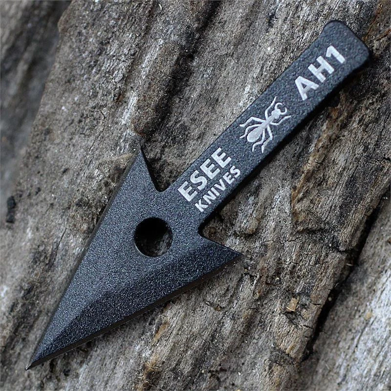 The ESEE AH-1 Arrowhead (ESEE-AH1-TG), a Tactical Gray traction-coated 1095 steel double-edged blade shown with its tang nubs and hole cutout for mounting to a stick.