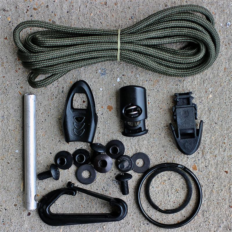The ESEE Izula Gear Complete Survival Kit (ESEE-IZ-KIT) laid out with its ambidextrous sheath, clip plate, paracord, cord lock, snap, split ring, fire flint, whistle, and instruction sheet. Knife not included.