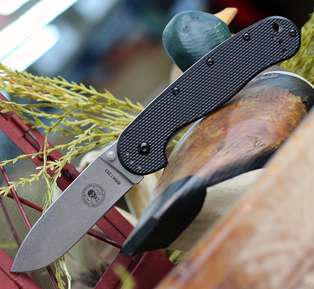 The ESEE Avispa (BRK1303) shown with its 3.50-inch SK-5 drop point blade in a stonewash finish and flat grind, modeled after the Laser Strike fixed blade, textured black polymer handle scale with stainless steel frame lock, and pocket clip for tip-up or tip-down carry.