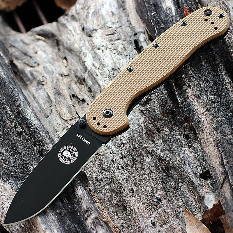 The ESEE Avispa (BRK1301CBB) shown with its 3.50-inch AUS-8 drop point blade in a black finish and flat grind, Coyote Brown polymer handle with steel frame lock, and pocket clip for tip-up or tip-down carry.