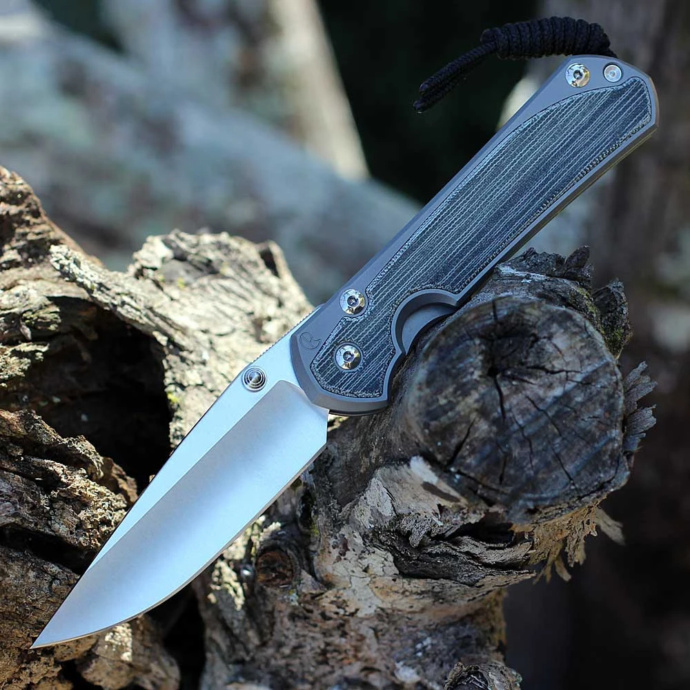 The Chris Reeve Large Sebenza 31 (L31-1652) shown with its 3.61-inch CPM MagnaCut hollow-ground drop point blade in a stonewashed finish, glass-blasted 6AL4V titanium handle with Black Canvas Micarta inlays, and its tip-up titanium pocket clip. The Reeve Integral Lock with ceramic ball interface is visible along the handle.