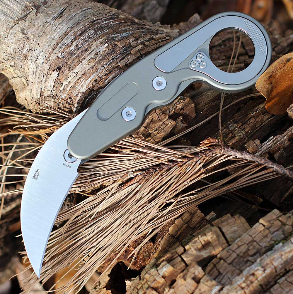 CRKT Provoke 4040G profile view showing 2.41 inch D2 satin hawkbill blade and silver/gray aluminum handle with Kinematic mechanism.