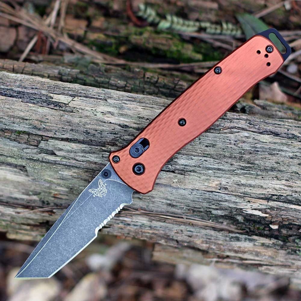 The Benchmade Bailout (537SBK-07) shown with its 3.38-inch CPM MagnaCut tanto blade in a DLC Battlewash finish with part serration, Burnt Copper anodized aluminum handle scales with a diamond-textured grip, and its tip-up reversible pocket clip. The AXIS Lock bar is visible along the spine of this ultralight tactical EDC folder.