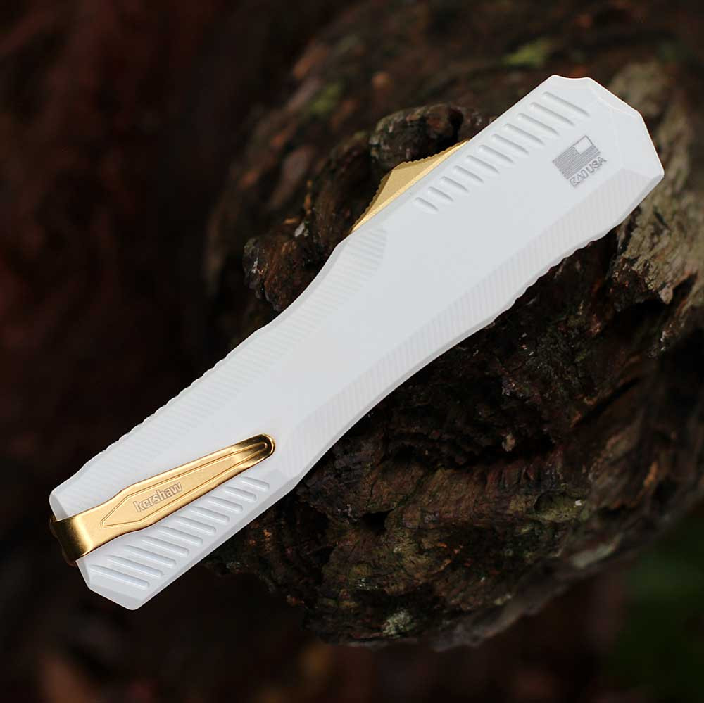 Detailed close-up of the white-anodized handle scales, black hardware, and the gold staircase-style thumb slide.