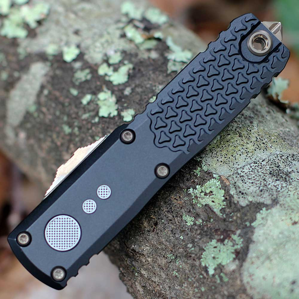 Microtech UTX-85 Gen IV 12321-1JM smooth black aluminum chassis — knurled texture, bronze hardware, OTF slide visible
