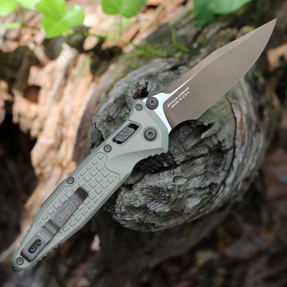 Microtech Socom RAM-LOK 160RL-1FRCG-C19Z23 — back view open, RAM-LOK crossbar lock and dual thumb studs visible, champagne gold frag aluminum handle