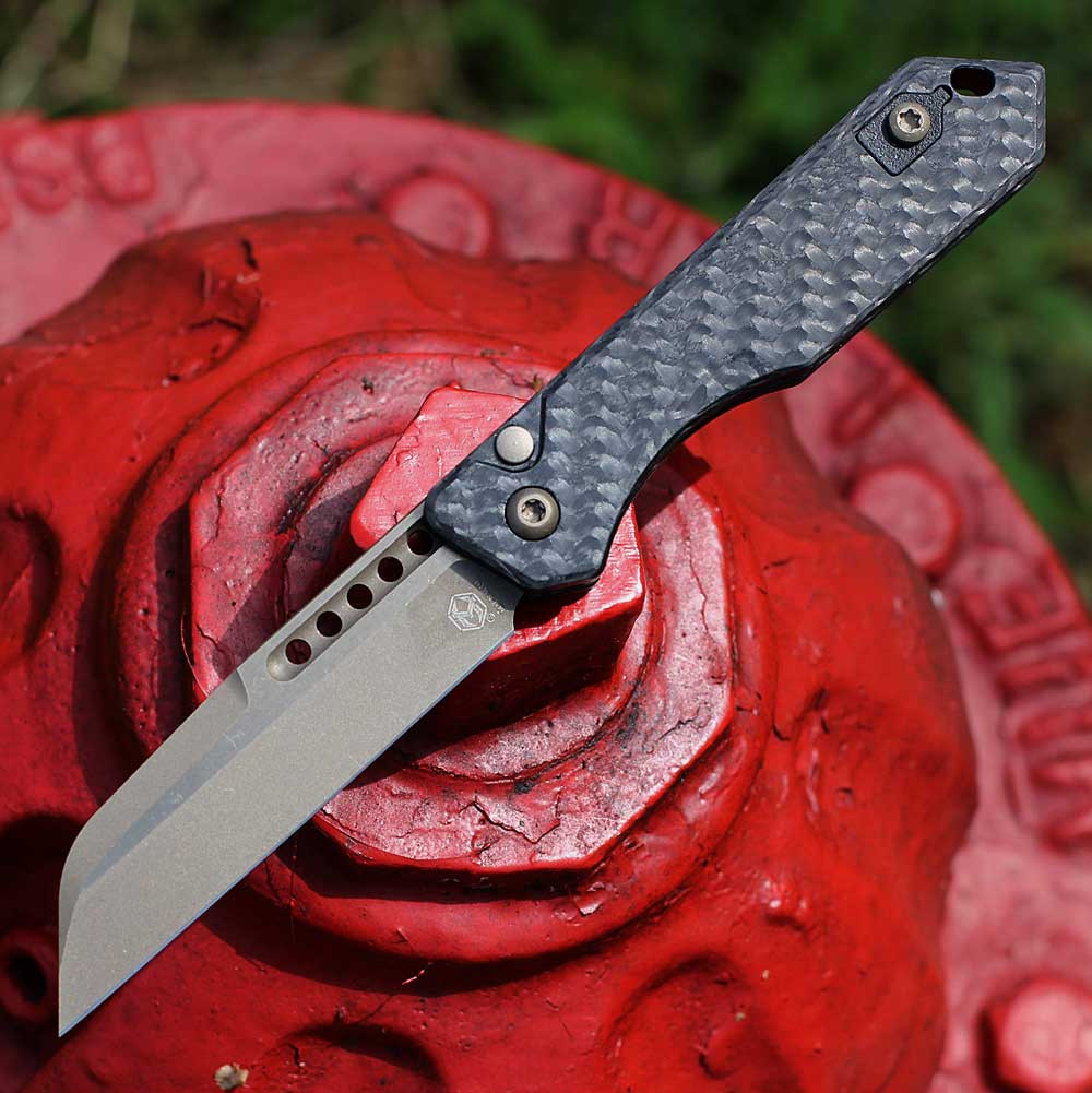 Heretic Jinn Auto H113-7A-CF closed — CPM MagnaCut bronze Wharncliffe, woven carbon fiber handle, Button Lock automatic, bronze hardware