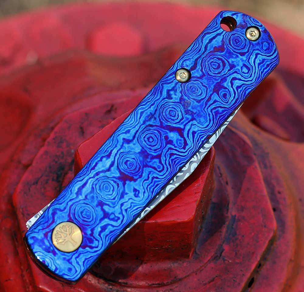Boker Germany BRLW Fulldress 110675DAM Mokuti handle — iridescent violet blue Ti-Cu-Zr alloy, gold pivot screws, Liner Lock, flipper
