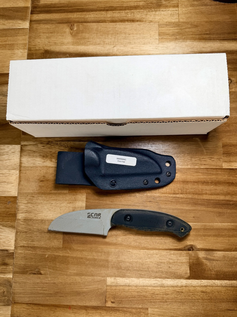 SCAR Blades Hawkeye Gray knife and box packaging shown together with black Micarta handle and Kydex sheath