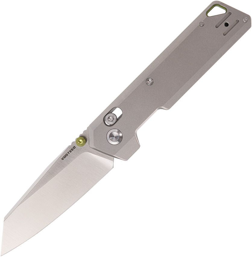 A Vosteed Parallel A3503 folding knife shown fully open. The 2.90-inch 154CM reverse tanto blade is deployed showing a flat grind and satin finish at 0.079 inches thin; the reverse tanto profile's upward-rising primary edge meeting the spine at a precise tip is clearly visible. The gray Grade 5 titanium handle is shown at 0.279 inches thin with green aluminum thumbstud and backspacer accents providing color contrast. Jimping is visible at the end of the handle. The Crossbar Lock mechanism is visible on the handle spine. The reversible stainless steel wire clip is mounted tip-up. Overall 7.04 inches, closed 4.13 inches, weight 2.29 oz. Made in China. Black nylon zippered storage case and box included.