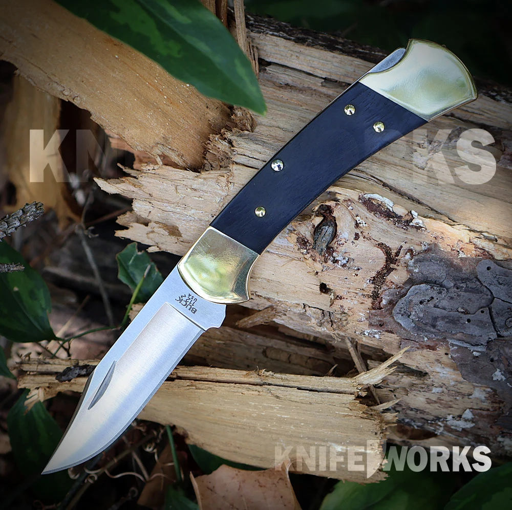 The Buck 112 Slim Heritage Elite (0112BRS19-B) shown with its MagnaCut clip point blade in a satin finish, genuine Crelicam® ebony handle scales with brass bolsters, and its deep-carry pocket clip in a slim 0.375" profile.
