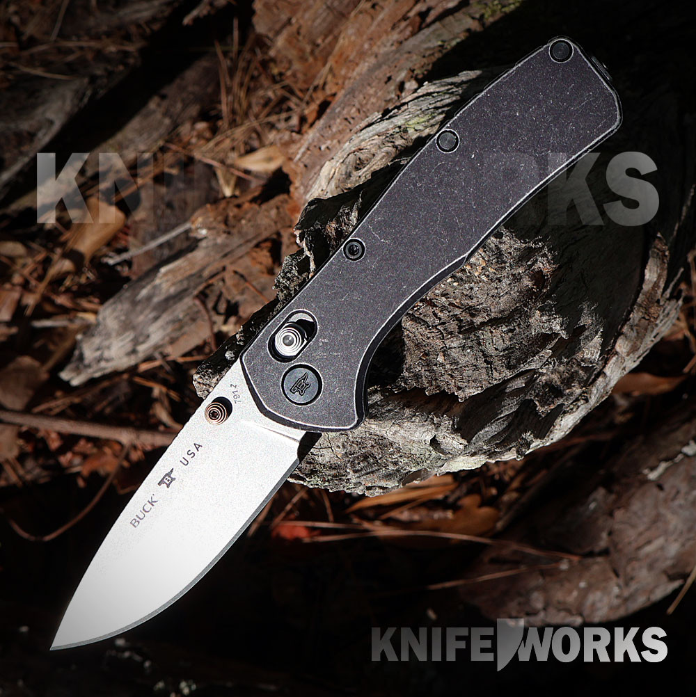 The Buck Range Trail Worn Elite (0791BKS2) shown with its 3.375-inch MagnaCut stonewashed drop point blade in a flat grind, tumbled black aluminum handle scales, and its deep-carry tip-up pocket clip. The crossbar lock mechanism is visible along the spine of this lightweight EDC folder.