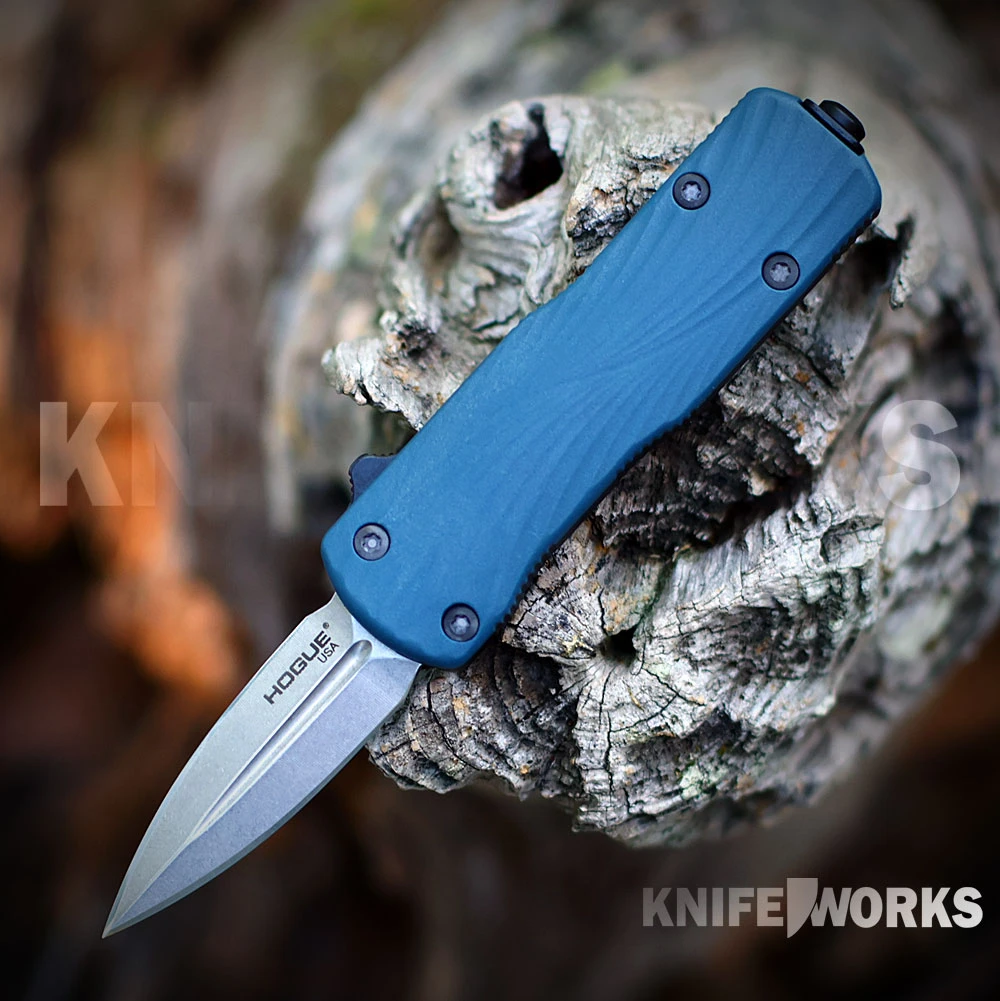The Hogue Micro Counterstrike (34703) automatic OTF knife shown with its 1.95-inch double edge CPM-MagnaCut blade in a stone tumbled finish, ornately milled 6061-T6 anodized aluminum case, Slate Blue glass fiber reinforced polymer cover, and deep carry reversible pocket clip.