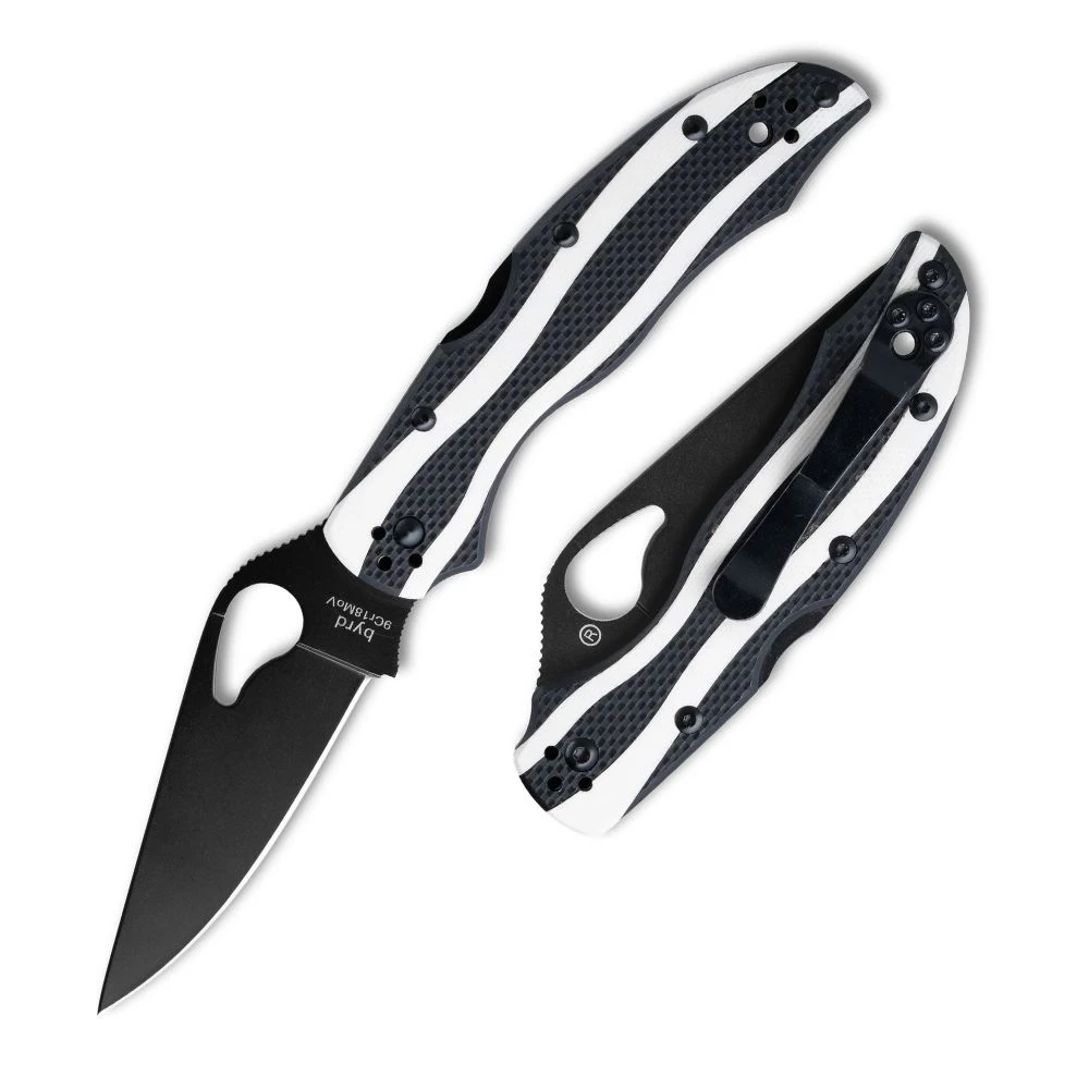 The Byrd Magpie Black Blade is shown open in profile, with a black-coated full-flat ground drop-point blade and a round thumb hole. The handle has black textured G10 scales with flowing white inlays and a black pocket clip.