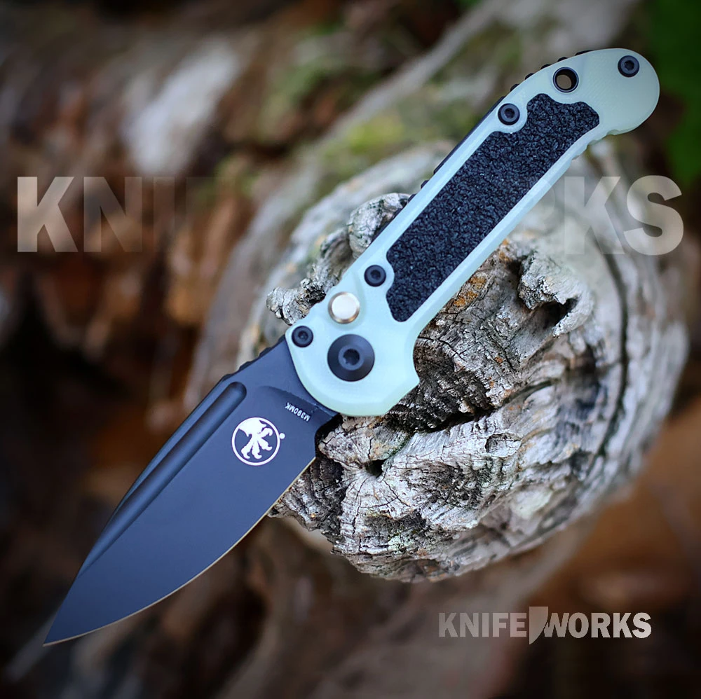 The Microtech LUDT Gen III is shown open in profile, with a black drop-point blade featuring a fuller and thumb ramp jimping. The jade green G10 handle shows traction inserts, the firing button, Torx screws, and a pocket clip.