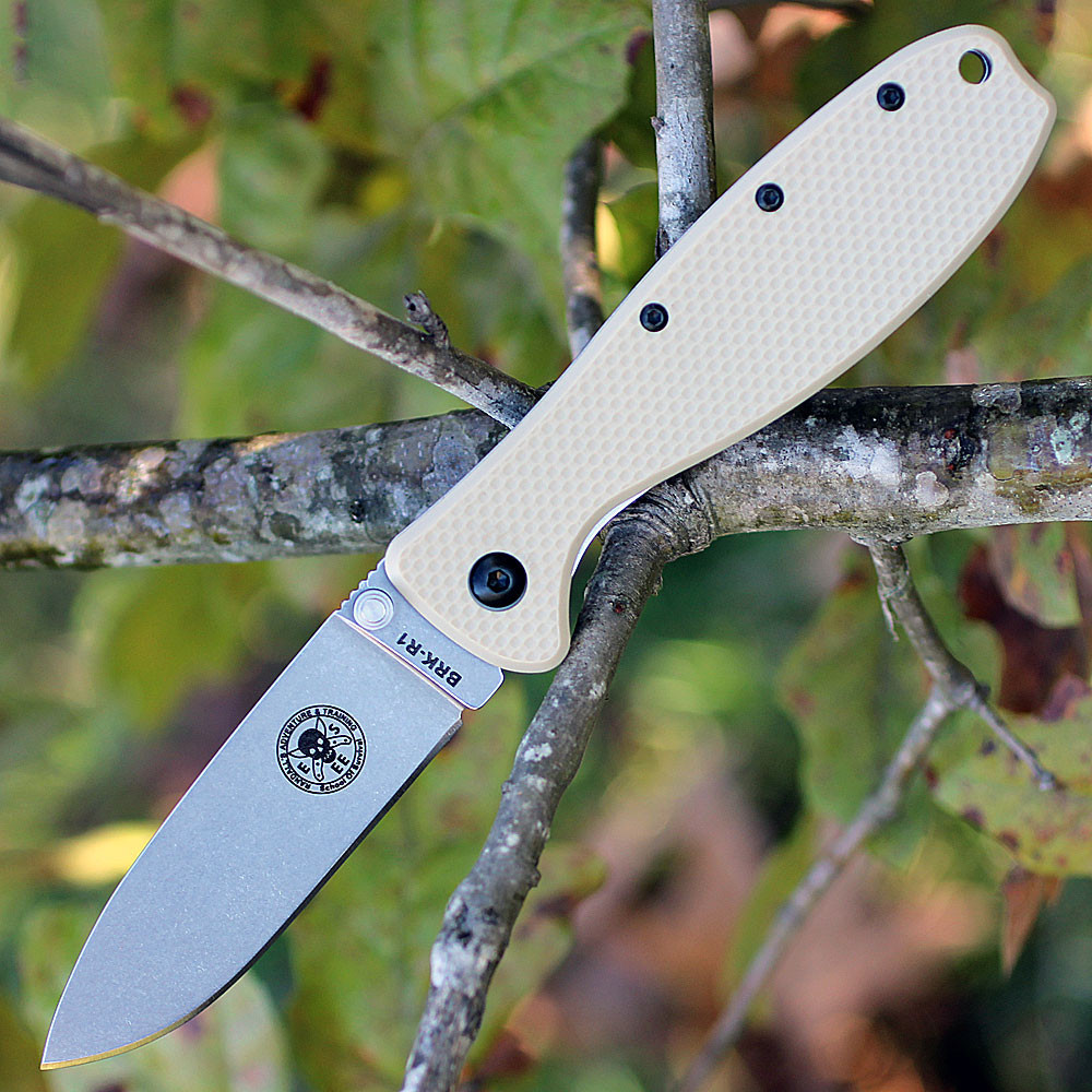 The ESEE Zancudo (BRKR2DT) shown with its 2.94-inch D2 drop point blade in a stonewash finish and flat grind, Desert Tan polymer handle with steel frame lock, and reversible pocket clip for tip-up or tip-down carry.