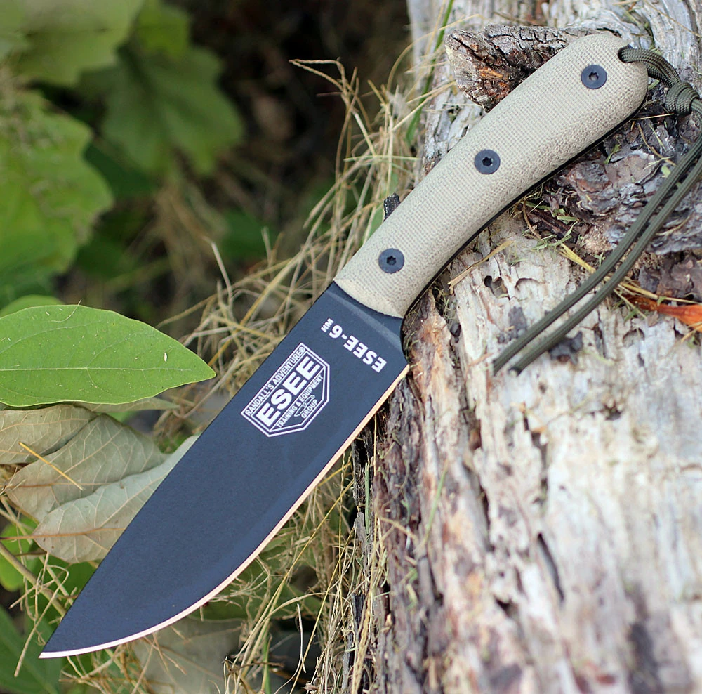 The ESEE-6HM (ESEE-6HM-B) shown with its 6.00-inch 1095 plain edge drop point blade in a black finish and flat grind, gray canvas Micarta handle with traditional profile, and its custom brown leather belt sheath.