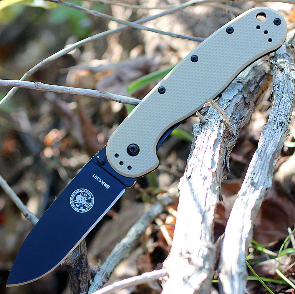 The ESEE Avispa (BRK1302DTB) shown with its 3.50-inch D2 drop point blade in a black finish and flat grind, Desert Tan polymer handle with steel frame lock, and pocket clip for tip-up or tip-down carry.