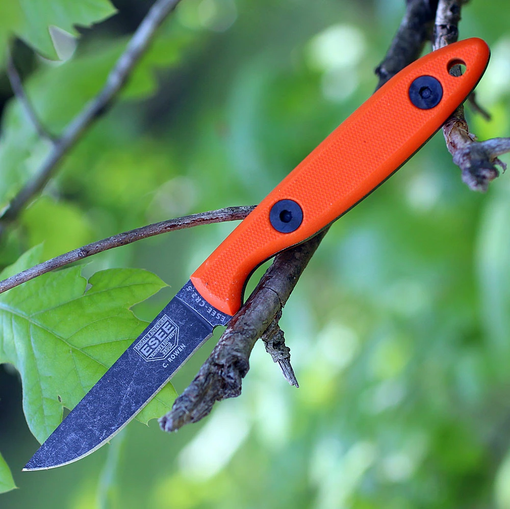 The ESEE Camp-Lore CR2.5 (ESEE-CR2.5-OR) shown with its 2.50-inch 1095 plain edge drop point blade in a tumbled black finish and flat grind, orange G-10 handle, and its improved brown leather bag sheath.