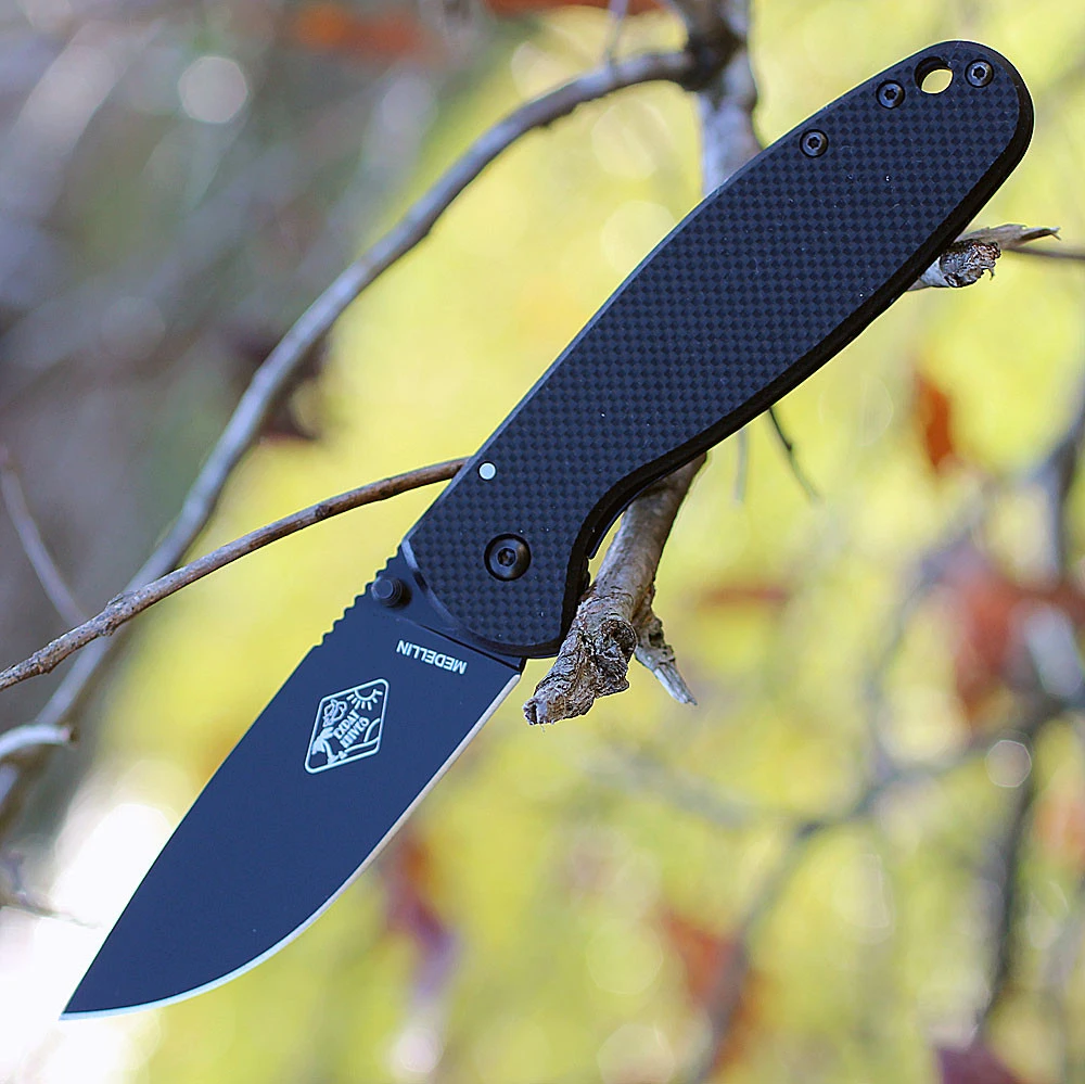 The Expat Medellin (MEDELLIN01B) shown with its 3.50-inch AUS-8 drop point blade in a black finish with thumb studs and spine jimping, textured black FRN handle with stainless steel frame lock, and its reversible deep-carry pocket clip.