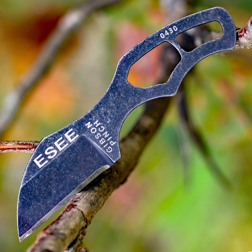 The ESEE Gibson Pinch (ESEE-PINCH) shown with its 1.30-inch 1095 plain edge Wharncliffe blade in a black oxide finish and flat grind, black skeletonized steel handle, and its molded black polymer neck sheath with magnetic retention.