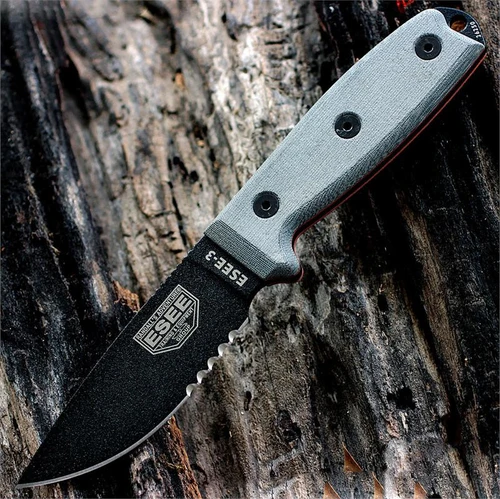 The ESEE-3 (ESEE-3SM-B) shown with its 3.88-inch 1095 black part serrated drop point blade and flat grind, gray Micarta handle scales with a modified pommel, and its injection-molded black plastic sheath.