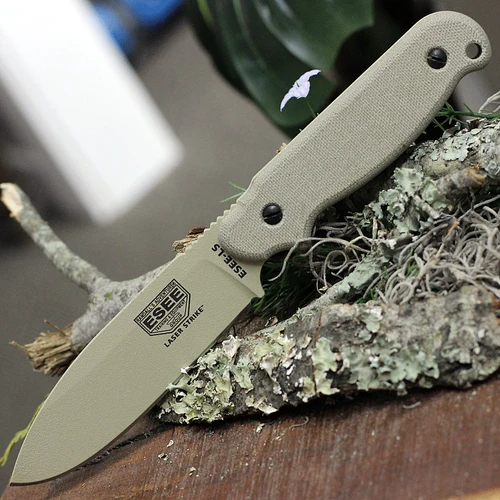 The ESEE Laser Strike (ESEE-LS-P-DT) shown with its 4.75-inch 1095 plain edge spear point blade in a Desert Tan finish and flat grind, tan Micarta handle with removable scales revealing the hollowed storage tang and bow drill divot, and its black Kydex sheath.