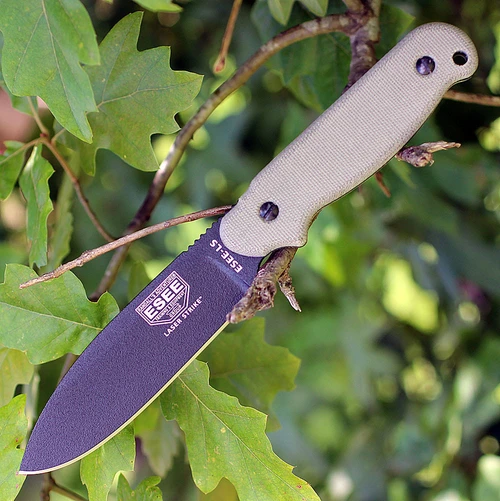 The ESEE Laser Strike (ESEE-LS-P-E) shown with its 4.75-inch 1095 plain edge spear point blade in a black finish and flat grind, tan Micarta handle with removable scales revealing the hollowed storage tang and bow drill divot, and its black Kydex sheath.