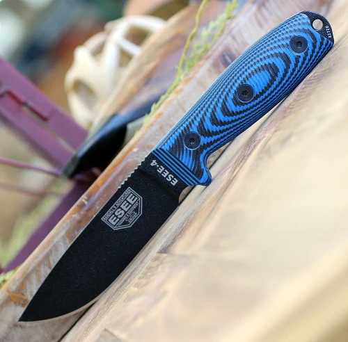 The ESEE-4 3D Handle (ESEE-4PB-008) shown with its 4.50-inch 1095 drop point blade in a black finish and tall flat grind, 3D blue and black G-10 handle scales, and its injection-molded black polymer sheath.