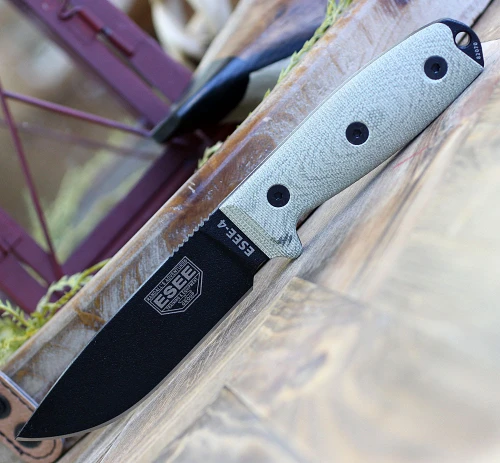The ESEE-4 3D Handle (ESEE-4PB-017) shown with its 4.50-inch 1095 drop point blade in a black finish and tall flat grind, 3D green Micarta handle scales, and its injection-molded black polymer sheath.
