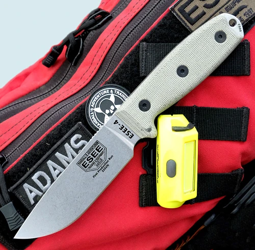 The ESEE-4 (ESEE-4P35V) shown with its 4.5-inch CPM-S35VN drop point blade in a stonewash finish and flat grind, tan Micarta handle scales, and its injection-molded black polymer sheath.