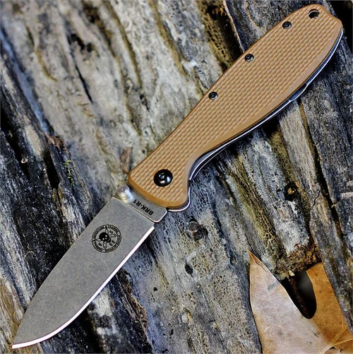 The ESEE Zancudo (BRKR1CB) shown with its 2.94-inch AUS-8 drop point blade in a stonewash finish and flat grind, Coyote Brown polymer handle with steel frame lock, and reversible pocket clip for tip-up or tip-down carry.