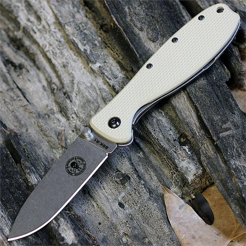 The ESEE Zancudo (BRKR1DT) shown with its 2.94-inch AUS-8 drop point blade in a stonewash finish and flat grind, Desert Tan polymer handle with steel frame lock, and reversible pocket clip for tip-up or tip-down carry.