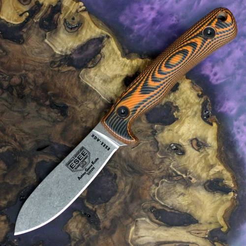 The ESEE Ashley Game Knife (ESEE-AGK35V-OR) shown with its 3.55-inch CPM-S35VN plain edge drop point blade in a stonewash finish and flat grind, full tang construction, textured orange and black G-10 3D-contoured handle, and its black Kydex sheath.