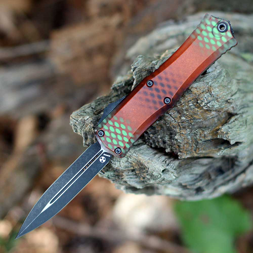 A Microtech Hera II Mini 1702M-10RX51S OTF automatic knife shown with blade deployed. The 2.95-inch Böhler M390MK bayonet blade is visible with a black stonewash flat grind finish; the false edge ground partway down the spine from the tip is visible creating the bayonet profile's characteristic point geometry. The orange X-51 aluminum slab handle is shown at 0.35 inches thin with the double-action thumb slide visible for deployment and retraction. Tip-down right carry clip mounted. Overall 6.90 inches, closed 3.95 inches, weight 1.90 oz. Made in the USA by Microtech Knives. ⚠️ OTF automatic — legal where permitted.