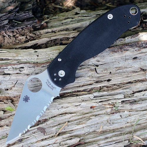 The Spyderco Para 3 C223GS is shown open. The tumble-finished, fully serrated clip point blade with a Trademark Round Hole extends from a black textured G-10 handle.