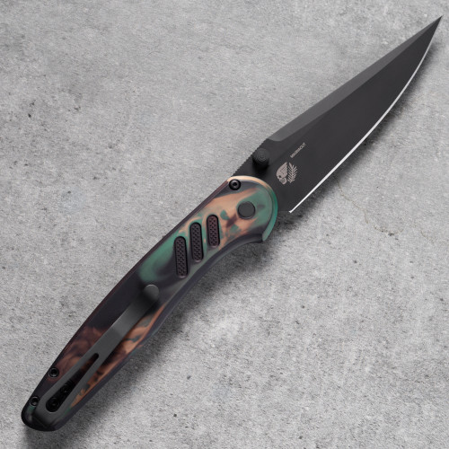 Pro-Tech Avalon PN1103-SHIPWRECK shown open on a gray concrete surface. The DLC black CPM MagnaCut drop point blade is fully deployed, with the Shipwreck-patterned aluminum handle displaying its copper, green, and earth-tone finish alongside the black hardware and clip.