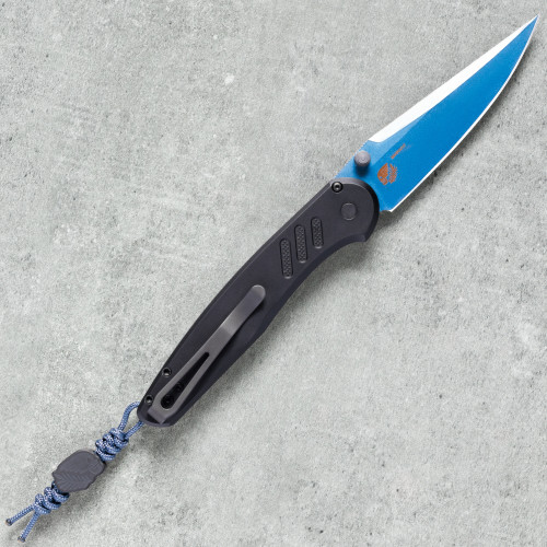Pro-Tech Avalon BSA26.Avalon.1 shown open on a gray concrete surface from a slightly elevated angle, displaying the full profile of the deployed sapphire blue PVD blade and black aluminum handle. The blade's drop point geometry and blue PVD finish are clearly visible.
