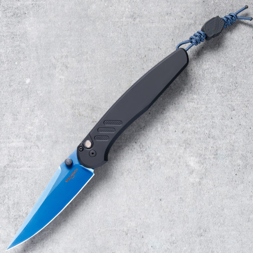 Pro-Tech Avalon BSA26.Avalon.1 shown open on a gray concrete surface with the sapphire blue PVD CPM MagnaCut drop point blade fully deployed. The vivid blue blade contrasts sharply against the solid black aluminum handle, with the lanyard visible at the base of the handle.