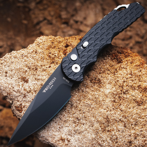 Pro-Tech TR-5 BSA26.TR5.1 shown open on a rough stone surface. The DLC black CPM-S35VN drop point blade is fully deployed, with the feather-textured black aluminum handle visible at the base of the frame. The all-black build against the natural stone background highlights the DLC blade finish and feather handle texture.