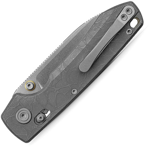 The Vosteed Raccoon TiSlim (A4506) is shown diagonally against a white background in the closed position, blade edge facing down. The stonewash gray drop point blade extends to the lower left with "VOSTEED" stamped near the ricasso. The acid wash gray titanium handle scales show the full crackle-cell texture pattern. Gold-toned pivot hardware, the crossbar lock bar, round pivot screw, and a secondary screw are visible on the show side of the handle.