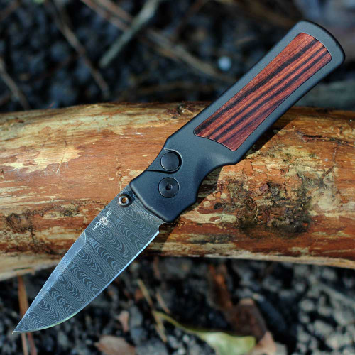 Hogue Saxum 24690-LIM open — Damascus drop point blade, matte black aluminum Kingwood handle, bronze thumb studs, Button Lock