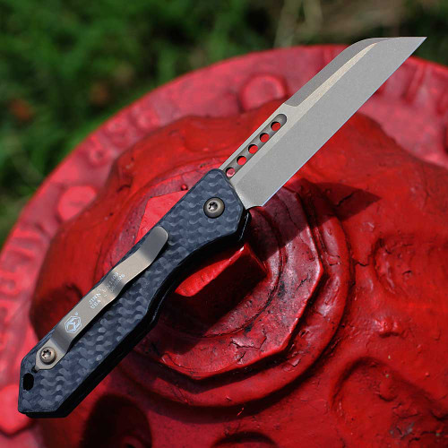Heretic Jinn Auto H113-7A-CF open — CPM MagnaCut 3.00 in bronze Wharncliffe blade, lightening holes, woven carbon fiber handle, Heretic logo