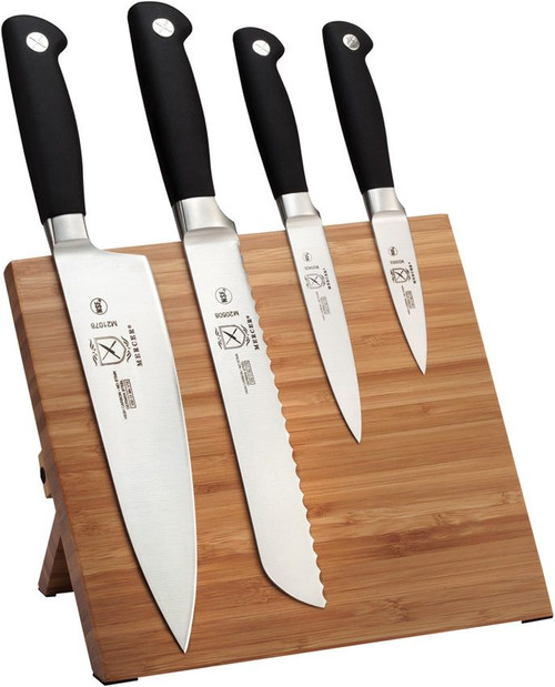Mercer Genesis 5-Piece Bamboo Set (MCR21960BM) shown against a white background. The set includes an 8.00" chef's knife, 8.00" wavy edge bread knife, 5.00" utility knife, and 3.50" paring knife — each with forged X50CrMoV15 satin blades with short bolsters and ergonomic black Santoprene handles. The sustainable bamboo magnetic board with recessed magnetic bars and anti-skid base pad is shown alongside the set.