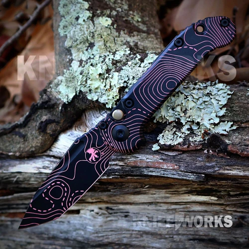 The Microtech LUDT Gen III (1136S-1TPBKPKCS) shown with its 3.4-inch M390 tanto blade in a Topographic Black/Pink Camo finish, matching Topographic Black/Pink Camo aluminum handle with black Torx hardware, and its tip-up right carry pocket clip. The push button opener and plunge lock are visible on this automatic folder. ⚠️ This is an automatic knife — verify legal status in your jurisdiction before purchasing.