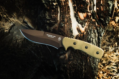 A TOPS Mountain Lion Field Edition TPMTLN02 fixed blade knife shown with blade and handle visible. The 5.50-inch 1095 high carbon steel blade carries a Brown Traction powder coat finish — a matte, earth-toned protective coating on the blade flats. The blade is 0.250 inches thick at the spine. The Green Canvas Micarta handle scales show a textured phenolic composite surface with black accent liners visible along the tang. The Chocolate Kydex sheath with rotating spring steel clip is shown alongside. Overall length 10.75 inches, knife weight 14.2 oz, 17.4 oz with sheath. TOPS Team design with 10th Mountain Division input. Made in USA.