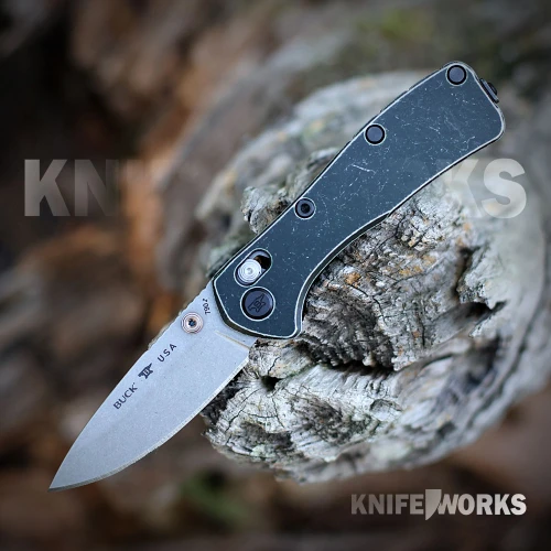 The Buck Mini Range Trail Worn Elite 0790GRS2 is shown open, featuring a stonewashed CPM MagnaCut drop point blade, crossbar lock, and tumbled green aluminum handle with a deep-carry pocket clip.
